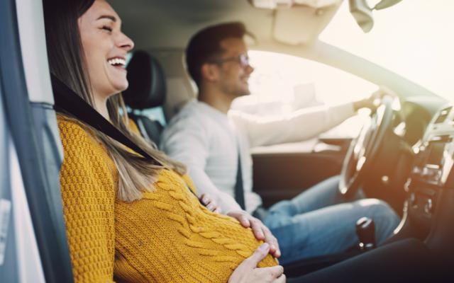 Mujer embarazada en un coche con su pareja.